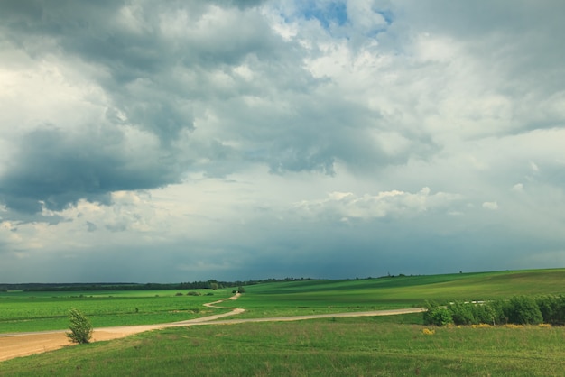 Beautiful landscape with green field and clouds.