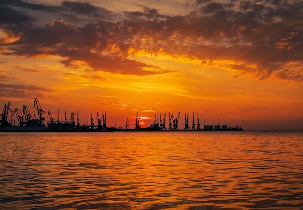 Beautiful landscape with seaport, fiery sunset sky and sea.  