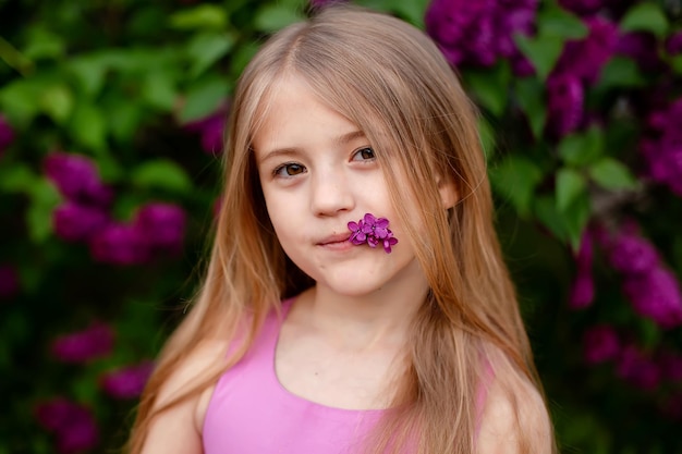 beautiful large portrait of a blonde girl with big eyes in a pink dress on a lilac background