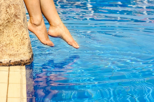 Photo beautiful legs of a girl near a swimming pool on the sea surface