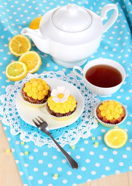 Beautiful lemon cupcakes and flavored tea on dining table close-up