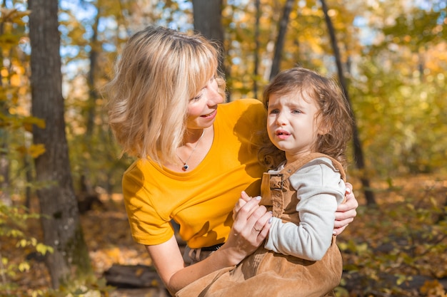 Beautiful lifestyle autumn photo mother and child walks evening in the park, warm sunlight.