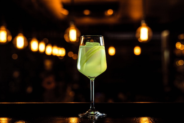 A beautiful light green cocktail with celery in a wine glass, bokeh lights, selective focus, horizontal