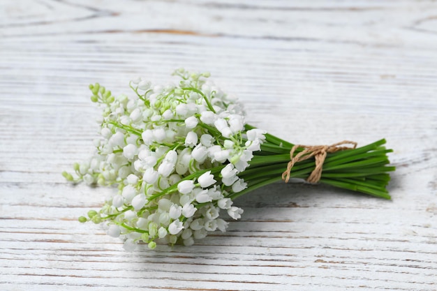 Beautiful lily of the valley flowers on white wooden table