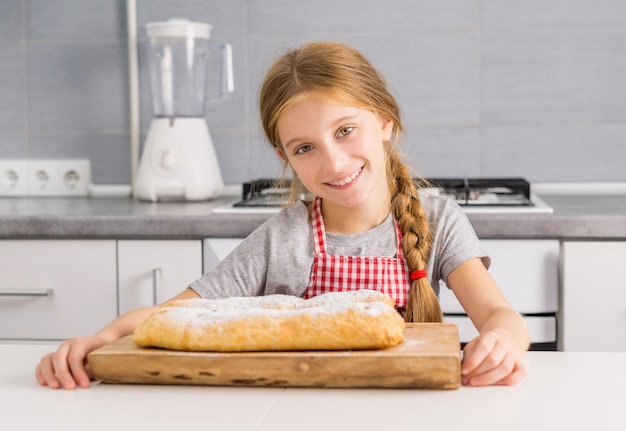 Beautiful litte girl with baked apple strudel on table