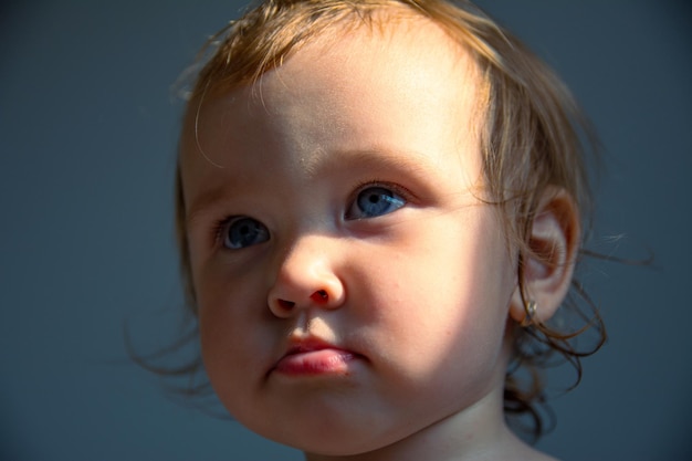 A beautiful little caucasian girl seriously looks into the frame with big eyes. Portrait of a child.