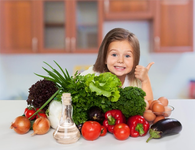 Beautiful little girl  in   cook hat with vegetables