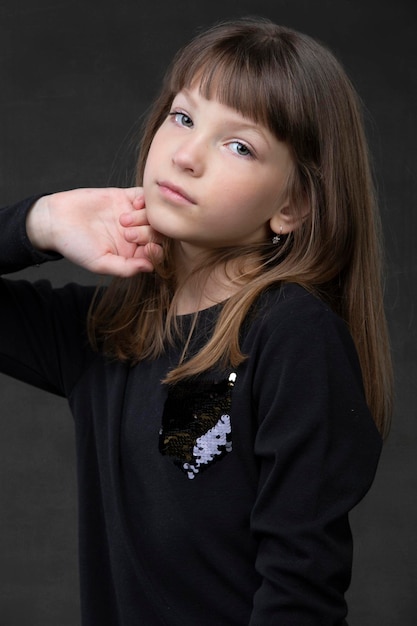 Beautiful little girl look at the camera on a gray background