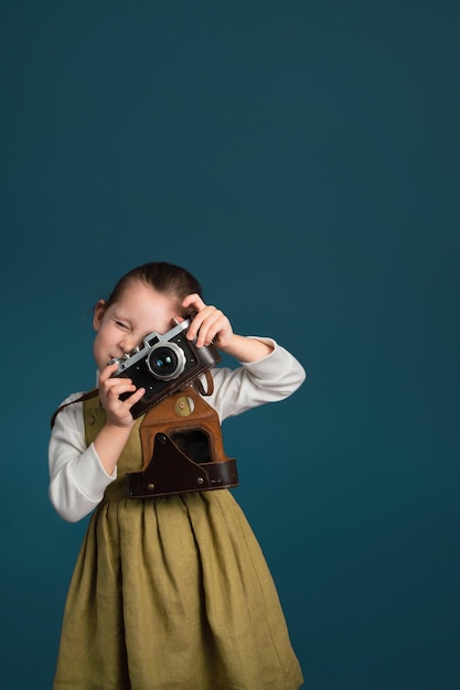 Beautiful little girl photographer with retro camera Studio vertical portrait with copy space