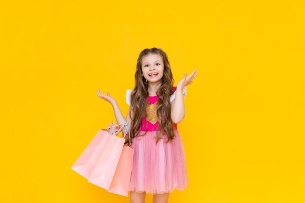 A beautiful little girl in a pink dress is happy to make new purchases from the store shopping in the store for spring new children's cooks for the promotion