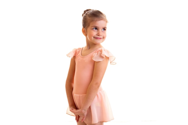 Beautiful little girl in pink dress with bundle dancing on white background in studio