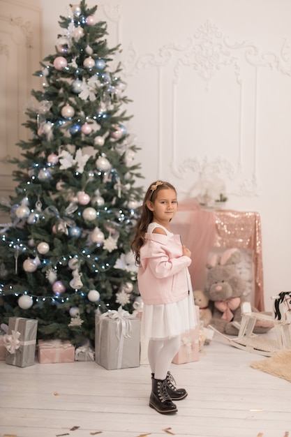 Beautiful little girl posing near the Christmas tree.