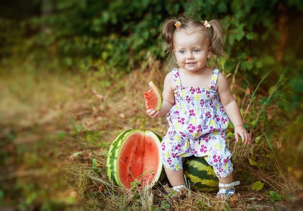 Beautiful little girl sitting on a watermelon. lifestyle and healthy eating.