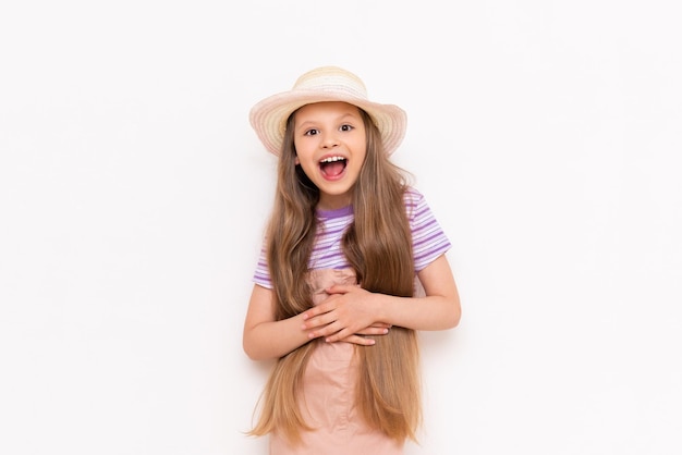 A beautiful little girl in a sundress and a straw hat is getting ready for a summer vacation Summer holidays for children White isolated background