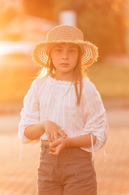 Beautiful little girl at sunset in a straw hat