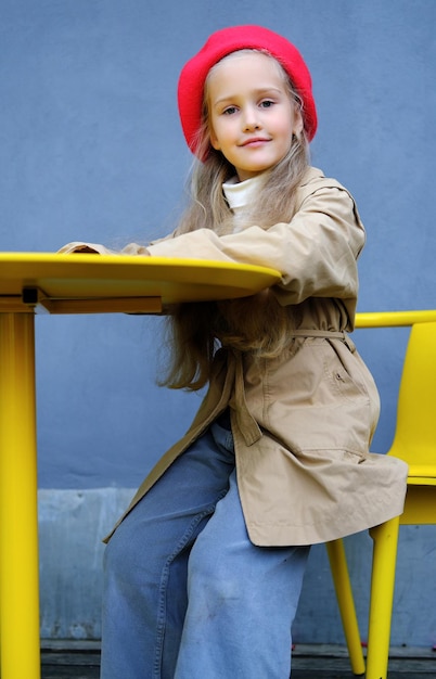 Beautiful little girl in a trench coat red beret and jeans