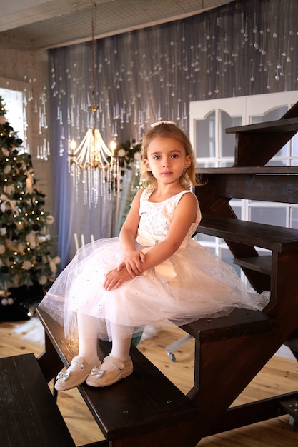 Beautiful little girl in white dress in modern Christmas interior