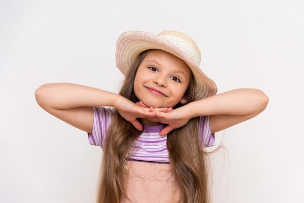 A beautiful little girl with long hair leans on her hands A child in a summer straw hat on a white isolated background