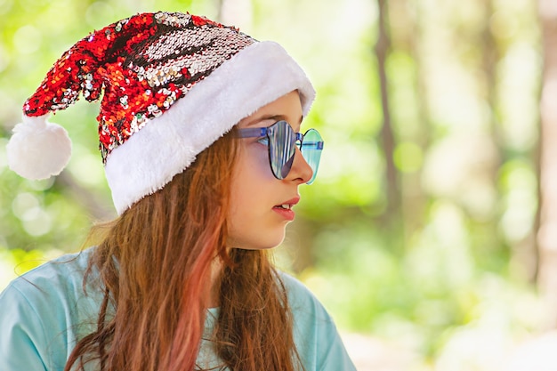 Beautiful little girl with long hair wearing a Santa Claus hat. Girl in Christmas