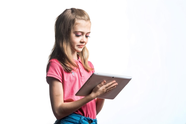 Beautiful little girl with a tablet computer in hands on a white background Emotions of the child