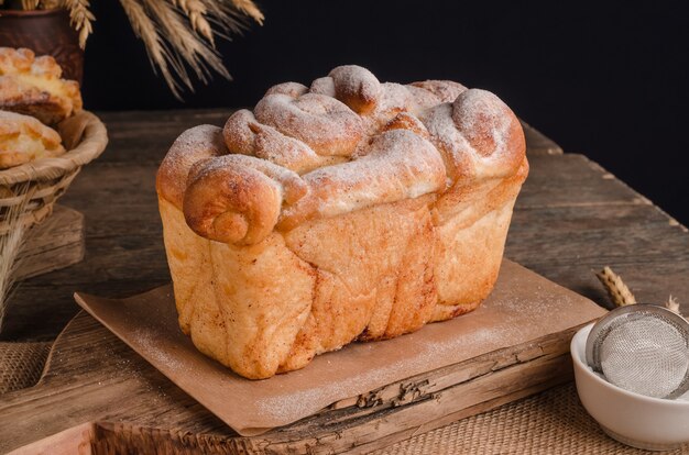 Beautiful loaf of white bread with curly top on wooden background