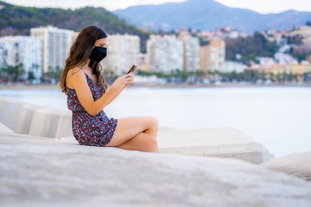 Beautiful long hair woman use the phone in the port with background sea