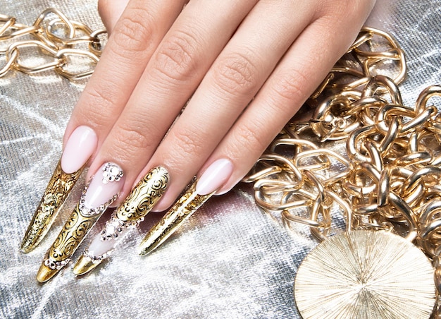 Beautiful long nails in a gold design with rhinestones Nail art