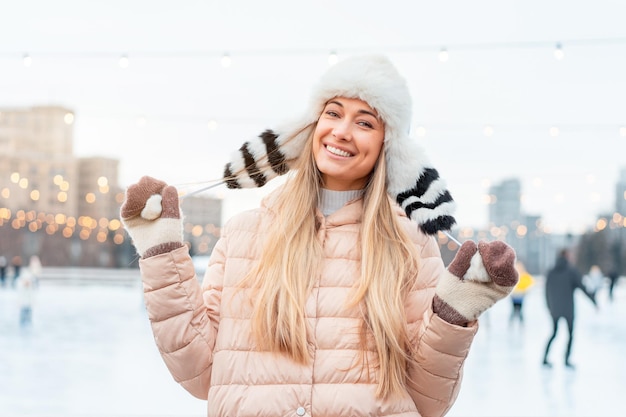 Beautiful lovely middleaged girl blonde hair warm winter jackets knitted glove stands ice rink background Town Square Christmas mood lifestyle