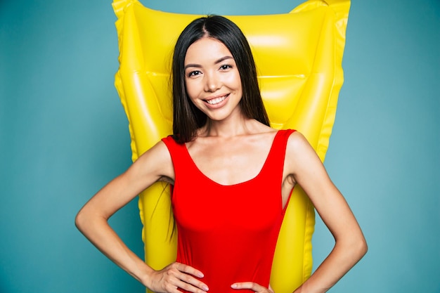 Beautiful lovely Sexy asian woman standing on blue background in swimsuit or bikini and smiling while posing. Summertime and vacation