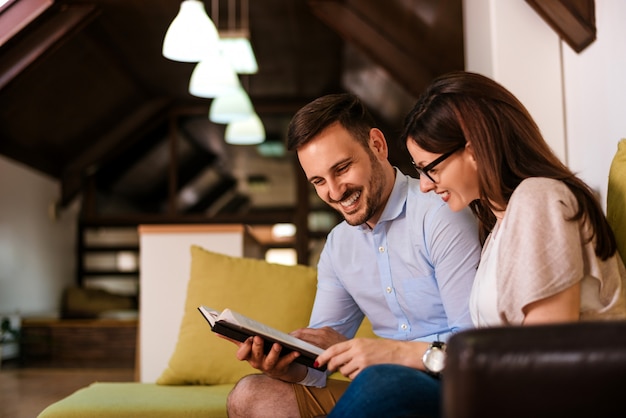 Beautiful loving couple reading a book on the sofa