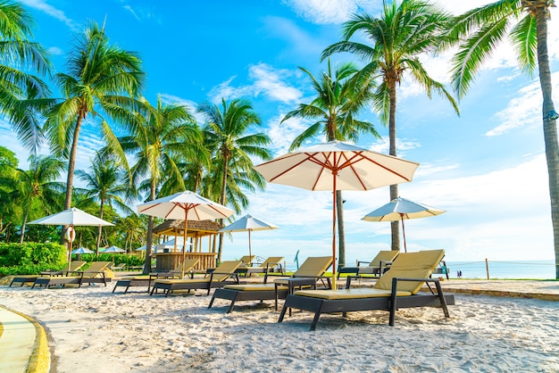 Beautiful luxury umbrella and chair around outdoor swimming pool in hotel and resort with coconut palm tree on sunset  or sunrise sky