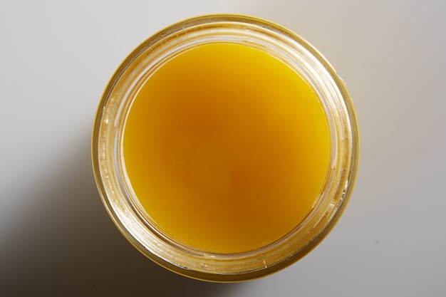 Beautiful macro image of honey in a jar from above. Appetizing golden drop of honey with a textured texture