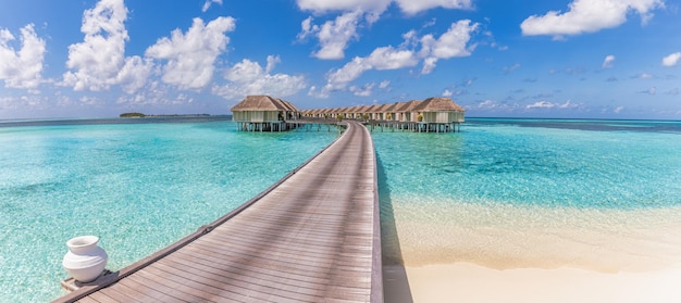 Beautiful Maldives water villa in blue lagoon and blue sky space. Panoramic summer landscape, ocean