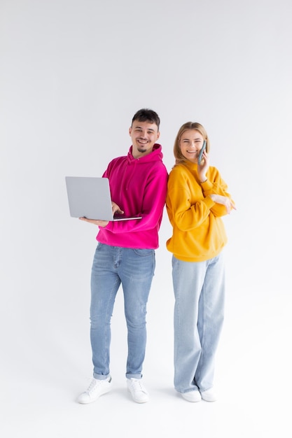 Beautiful man and woman on white background using laptop and smartphone