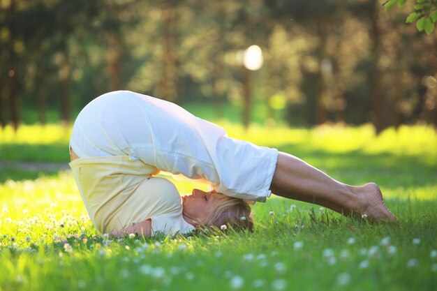 Beautiful mature woman practice yoga in the park