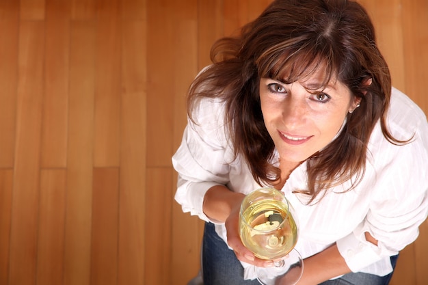 A beautiful mature woman with a glass of white wine.