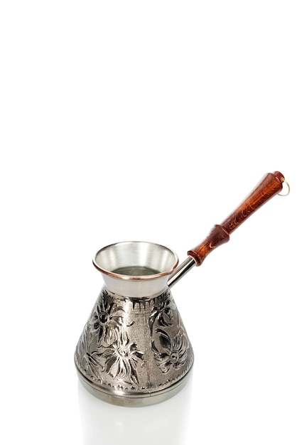 Beautiful metal cezve with an ornament and a wooden handle Traditional preparation of aromatic drink Isolated on white background Vertical