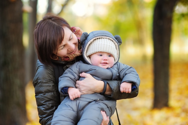 Beautiful middle aged woman and her adorable little grandson in the autumn park