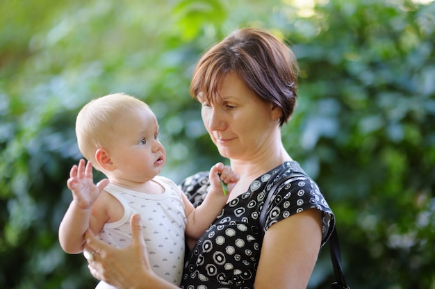 Beautiful middle aged woman and her adorable little grandson at the summer park 