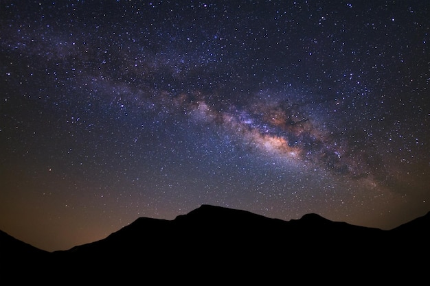 Beautiful milky way galaxy and silhouette of high moutain on a night sky before sunrise