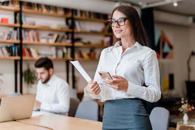 Beautiful millenial business woman with phone in the office