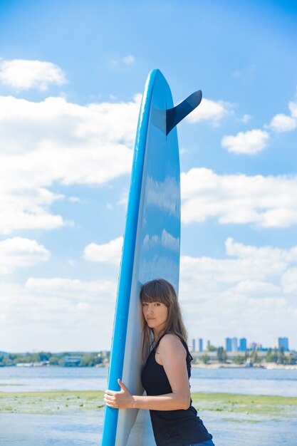 Beautiful millennial woman with a SUP board on the river. Active rest concept.