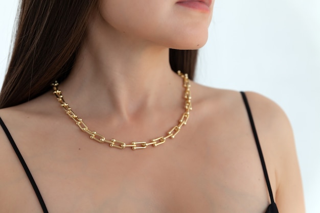 Beautiful model brunette in modern gold metal necklace chain