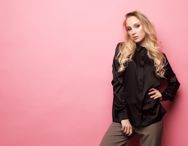 Beautiful model pose for a photo in trendy clothes over pink background