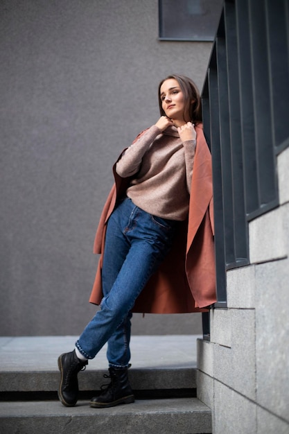 A beautiful model in a sweater and jeans stands on the steps Place for an inscription