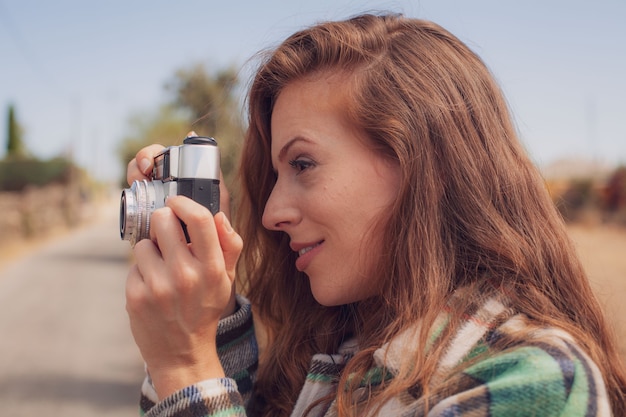 A beautiful model takes a photograph with an analog camera