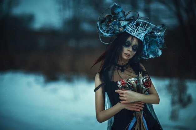 Beautiful model wearing black dress is posing on a snow