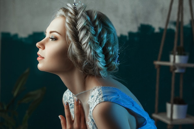 Beautiful model wearing light blue dress is posing in a studio