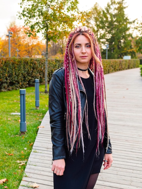 Beautiful model with long pink and beige dreadlocks and pigtails in a park in early fall