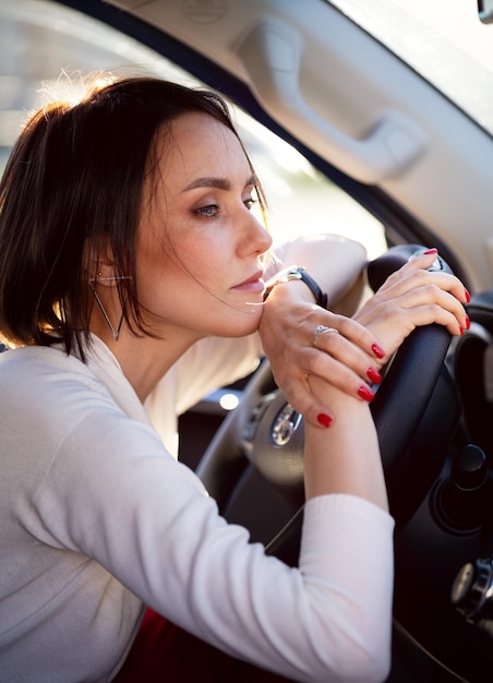 Beautiful modern fashionable girl sitting in her car and thinking